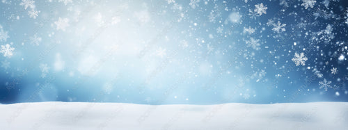 Winter snow background with snowdrifts, with beautiful light and snow flakes on the blue sky, beautiful bokeh circles, banner format, copy space.