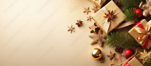 Christmas Decoration Composition on Light Gold Background with Beautiful Golden Gift Box with Red Ribbon, Fir Branches, Cones, Stars, Top View, Copy Space, Banner Format.