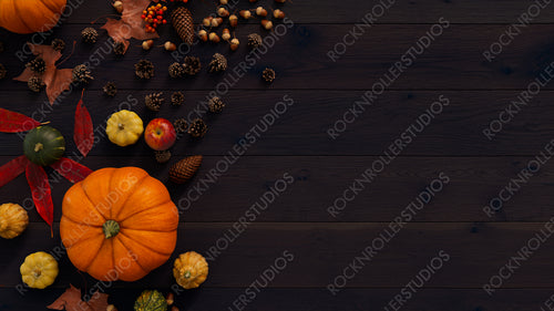 Top down view of Dark wood Tabletop with leaves, Pumpkins and Pine cones.