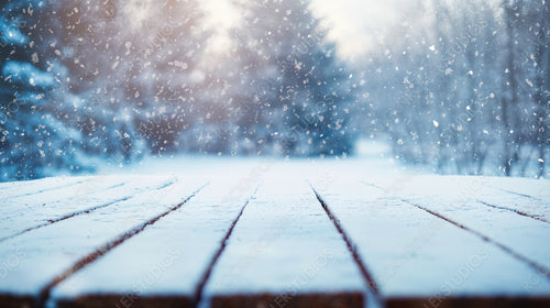 Snowy Wooden Surface with Falling Snowflakes and Blurred Winter Forest Background