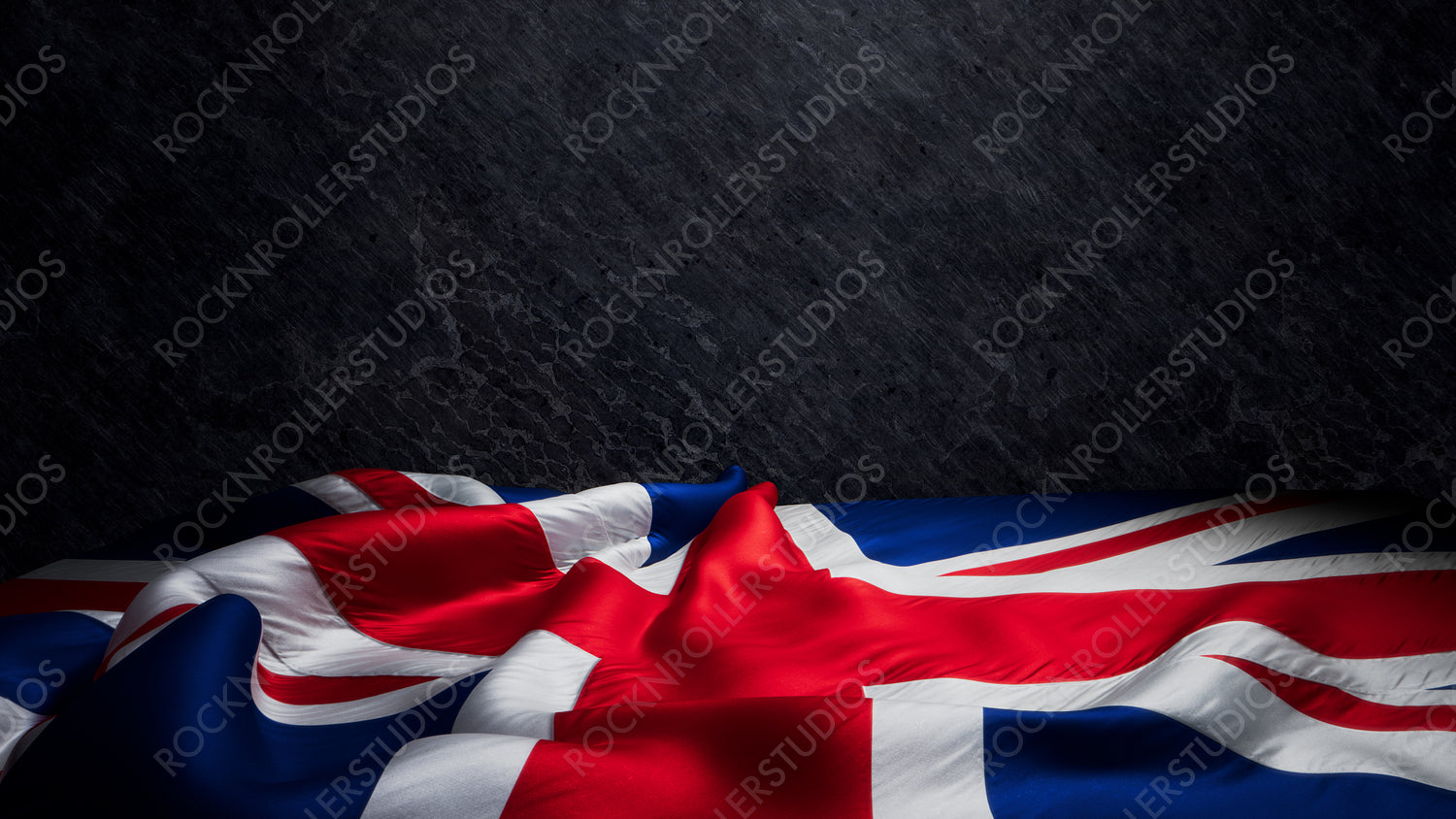Dramatic Union Jack Flag Draped Against a Dark Textured Stone Background with copy-space