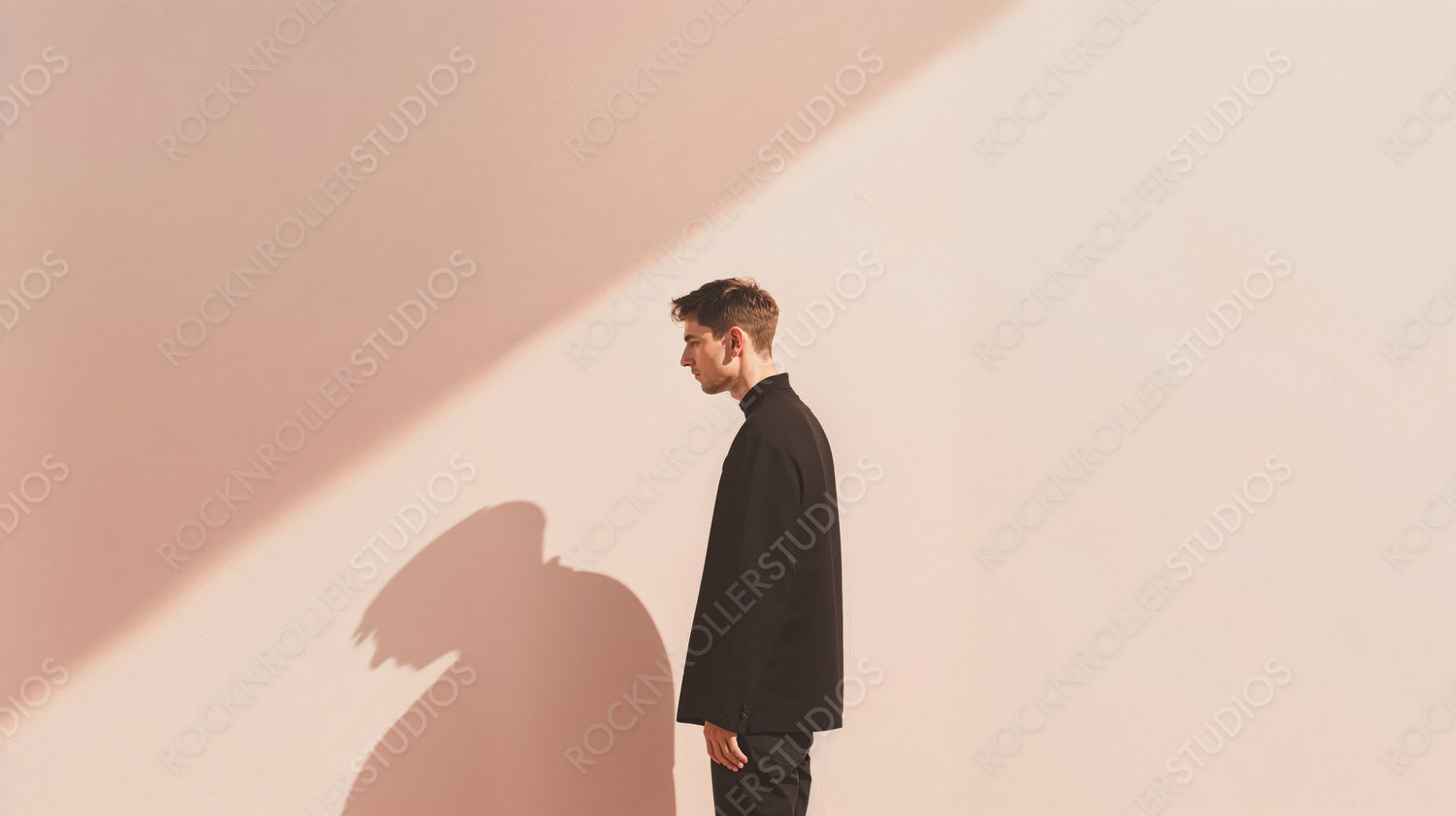 Contemplative Man in Dramatic Lighting Against Pastel Wall