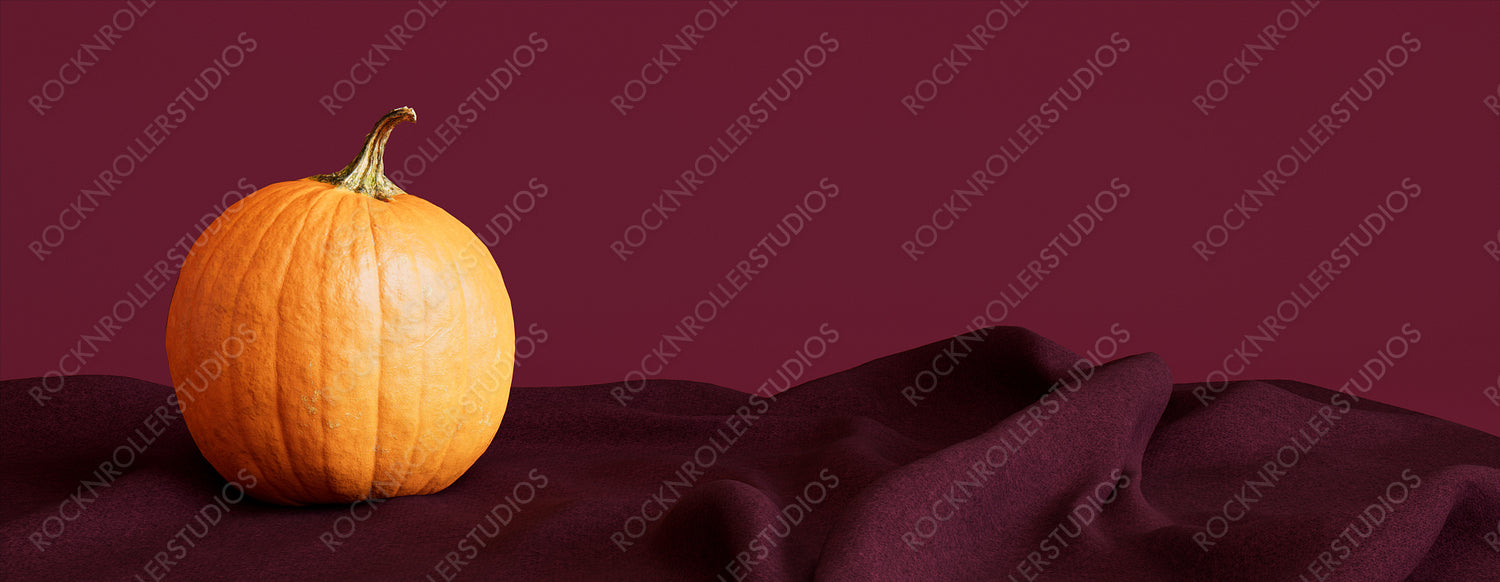 Pumpkin with Burgundy colored Fabric. Fall themed Background with copy-space.